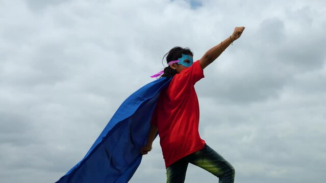 Back view shot of pre teen kid with super kid fantasy dress or costume standing like flying with hand gesure againt cloud - concept of dream, imagination and powerful