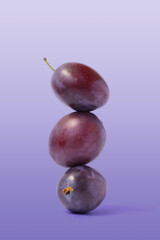 Ripe balancing plum on purple background. Equilibrium food balance.