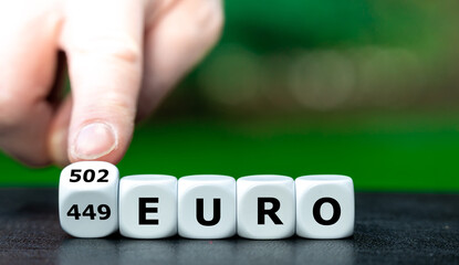 Hand dreht Würfel und ändert den Ausdruck 449 Euro in 502 Euro. Symbol für die Einführung des Bürgelgeldes von 502 Euro im Januar 2023 in Deutschland.