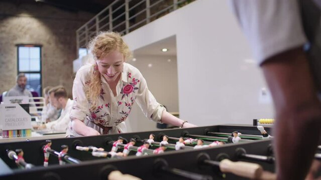 Business people in office taking a break, playing table football
