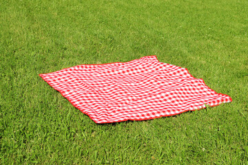 Checkered picnic tablecloth on fresh green grass outdoors