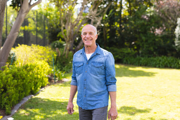 Portrait of senior caucasian men wearing blue shirt and standing in the garden