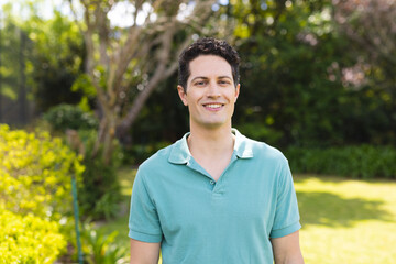 Portrait of young caucasian men wearing blue shirt and standing in the garden