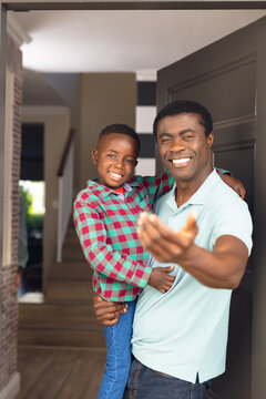 Vertical picture of happy african american son and father welcoming somebody outside the house