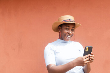 young black African model smiling looking at camera with mobile phone in hand