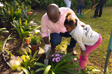 African american father and daughter spending time together in the garden and gardening