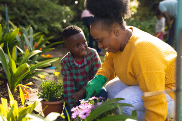 African american mother and son spending time together in the garden and gardening