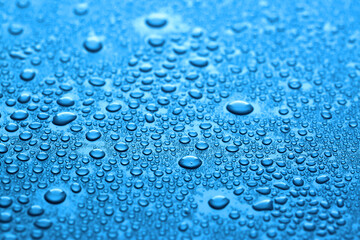 Many water drops on dark dusty blue background, closeup
