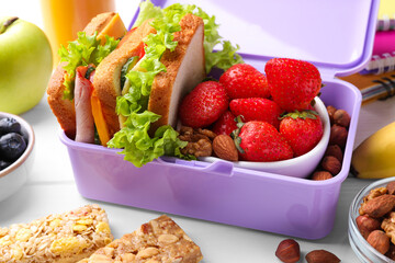 Lunch box with healthy food for schoolchild on white wooden table, closeup