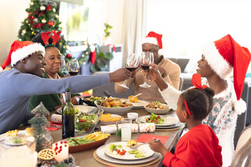 African american family spending time together having christmas meal and drinking wine