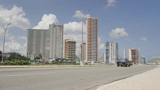 Cars traveling the malecon street of Havana City, in Cuba - Modern Vedado District with skyscraper hotel buildings