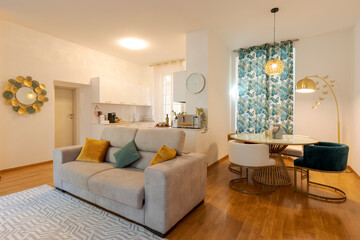 Modern open space in elegant apartment. There is a comfortable sofa in the foreground and the dining room behind