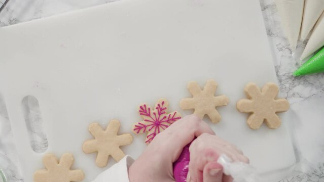 Time lapse. Flat lay. Stp by step. Icing Christmas tree-shaped sugar cookies with green royal icing.
