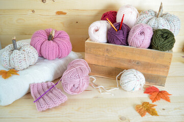 Fototapeta na wymiar crochet woolen pumpkins on white woolen blanket with woolen balls in wooden box with autumn leaves and crochet hooks