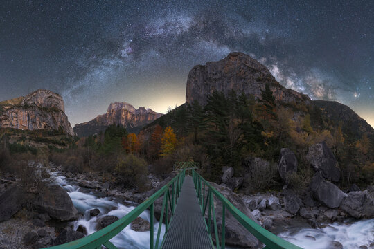 Amazing night starry sky over bridge in mountains