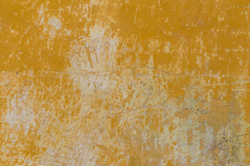 Yellow wall with a scratched, damaged, rough, painted texture. Close up background design element.