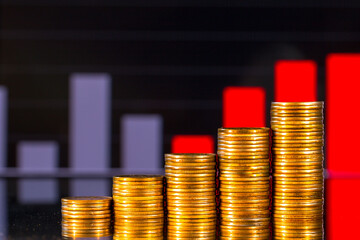 Stacks of golden coins on the background of a blurred business financial graph. Digital business and stock market financial indicator.