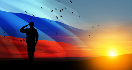 Silhouette of russian soldier in uniforms on background of sunset sky with the Russian flag....