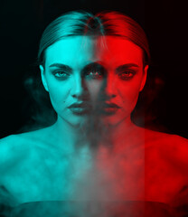 Studio portrait of beautiful woman blowing smoke from mouth in RGB color split. RGB effect make reflection of model face in red and blue colors. Abstract and futuristic looking style