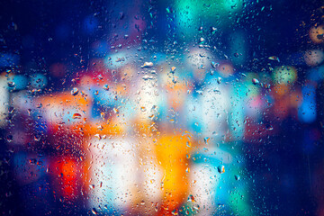City view through a window on a rainy night,Rain drops on window with road light bokeh, City life in night in rainy season abstract background. Focus on drops on glass