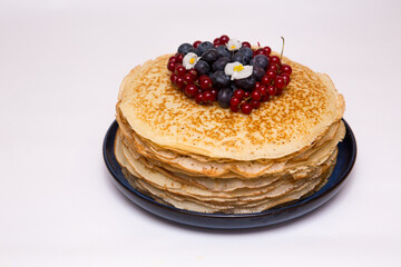 a large stack of pancakes with red sweet berries