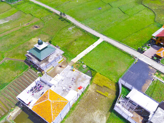 Fototapeta premium Cicalengka, West Java, Indonesia - 27 September, 2022 : Abstract Defocused Blurred Background Aerial photo of a mosque in the middle of a rice field 