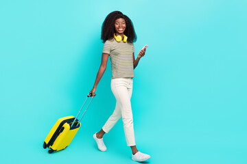 Full body profile photo of attractive lady hold telephone suitcase walking isolated on teal color background