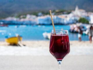 Copa de vino tinto frente a la playa de Cadaqués