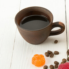 Cup of coffee and marmalade candy on white .