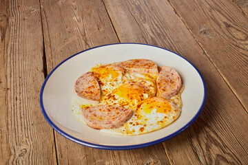 Fried eggs with sausage on a wooden table. Greater depth of field