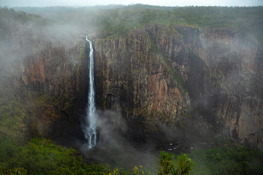 aerial view of a huge, murky waterfall in the mist, wallaman falls - the largest waterfall in australia; - Powered by Adobe