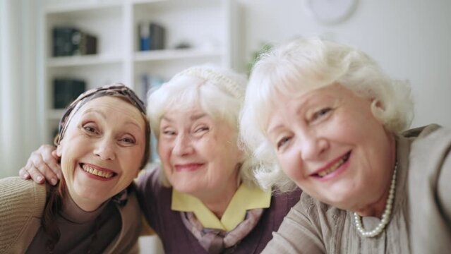 Senior women looking at camera while taking selfie, group portrait, best friends