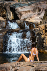 Fototapeta na wymiar a beautiful girl in a white bikini swims in a natural pool in jourama falls; relaxing in paluma range national park in queensland, australia; cascading waterfalls with pools