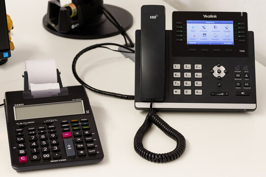 Treuchtlingen, Germany, 09 Oktober 2022: Office scene with Yealink T46S phone is an IP business phone that is now used widely in the world and a casio sektop calculator.