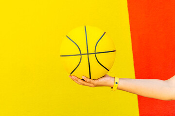 woman holding yellow basketball on colorful background