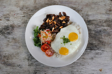 US Beef Tapa with sunny egg and rice with tomato served in dish isolated on wooden background top...