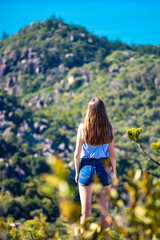 beautiful girl stands on top of mountain overlooking magnetic island panorama; vacationing on magnetic island, queensland, australia