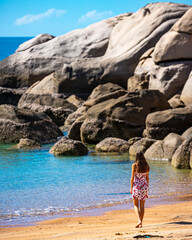 a beautiful long-haired girl in a dress relaxes on a paradise beach on magnetic island; a beach with massive rocks and turquoise water; relaxing on magnetic island, queensland, australia