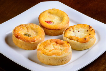 Mini quiches snacks of assorted flavors on a white plate.