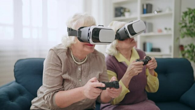Two senior women in VR headsets playing video game, virtual reality, hobby
