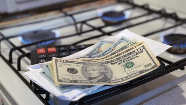 Pile money dollars and a calculator on the background of a burning gas stove. Concept of tariff or cost shortage and gas crisis struggle for world markets. Gas prices in Europe and USA. Nord Stream