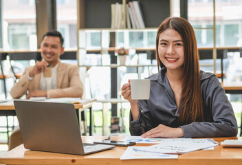 HR workers sit back and relax with coffee on their desks with their computers and documents laying around.