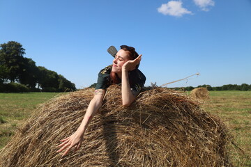 Naklejka na ściany i meble girl resting in a field on a haystack