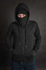 Fototapeta na wymiar Unrecognizable man in the black hoody with hood wearing balaclava mask