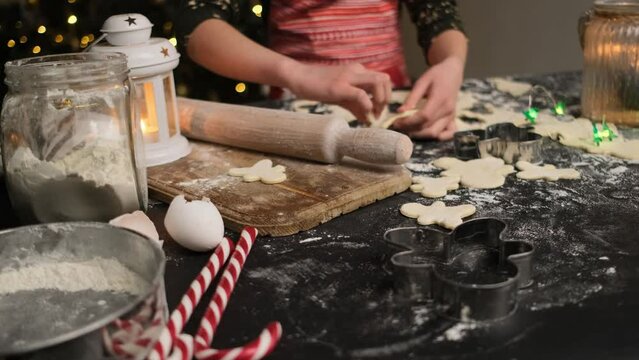 Girl cutting gingerbread men from dough using forms for cookies at home