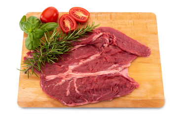 Raw beef steak on wooden cutting board with basil, rosemary and cherry tomatoes isolated on white, dolly shot