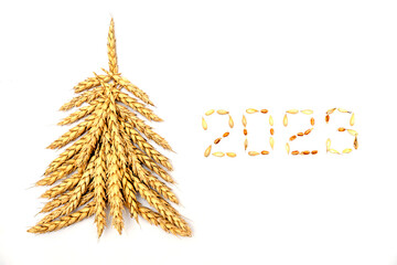 Creative Christmas tree made of wheat ears.New year 2023 made of grains on a black...