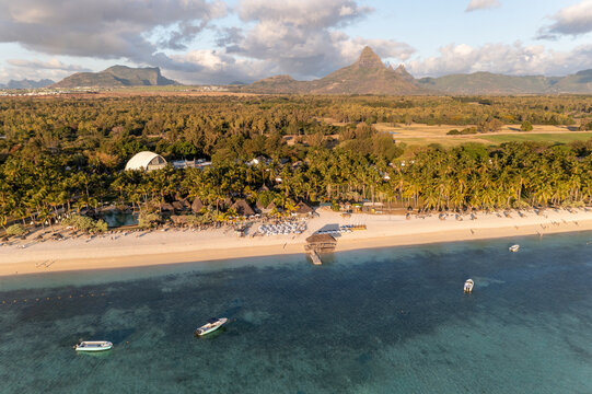 Aerial view of a beach with resort in Flic en Flac with a mountain range in the background and anchored boats. at sunset, Mauritius, Africa.