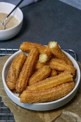 close up of churros with sugar in white bowl, top view