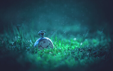 Vintage mechanical watches are buried in the ground. A cold morning in the grass with a round...